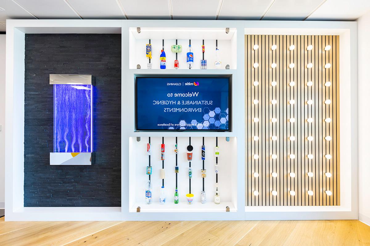 A wall displaying various empty containers for household products, 灯, water jets and a flat-screen TV. Part of the Mitie清洁 and Hygiene Centre of Excellence