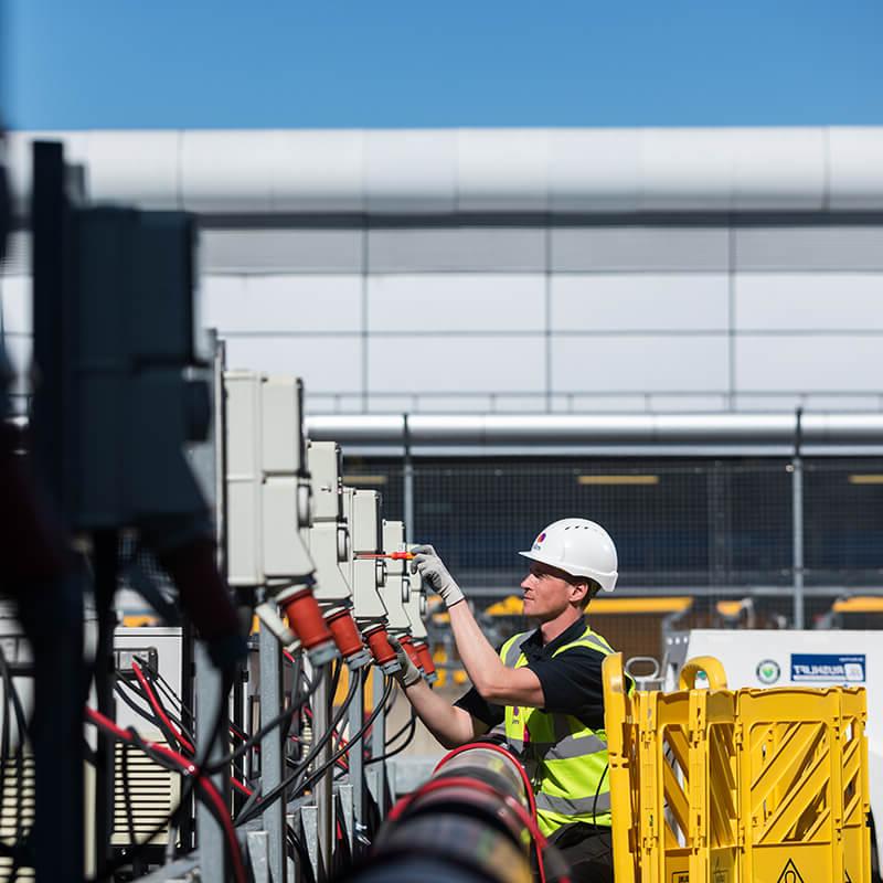 Mitie male engineer using a screwdriver on electrical wiring at Heathrow airport