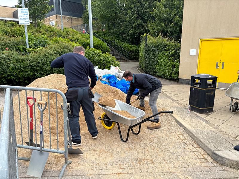 Mitie colleagues filling a wheelbarrow with gravel